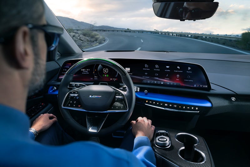 Front View of the 2026 OPTIQ-V Driving Through the Dusk Utilizing its Headlights | Kolar Cadillac in Hermantown MN