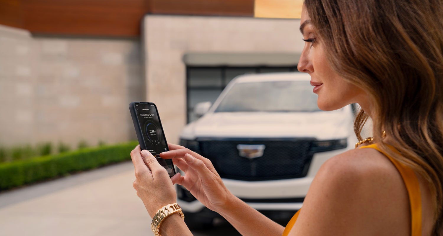 lady checking her mobile with a Cadillac vehicle background | Kolar Cadillac in Hermantown MN